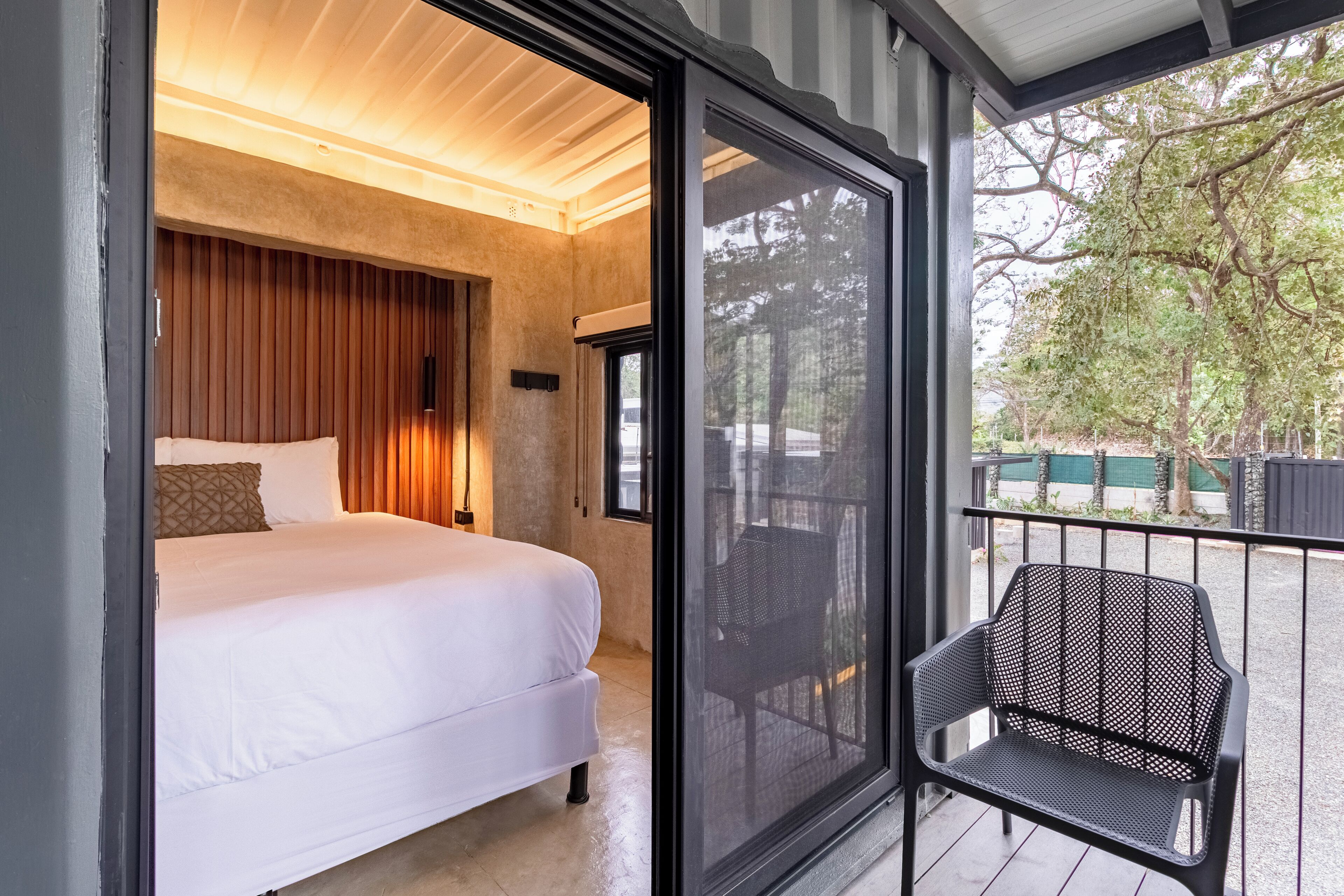 Un dormitorio con cama, mesita de noche y ventana grande.