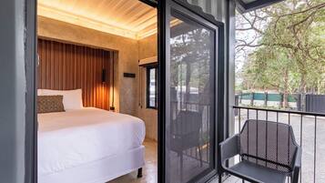 Un dormitorio con cama, mesita de noche y ventana grande.