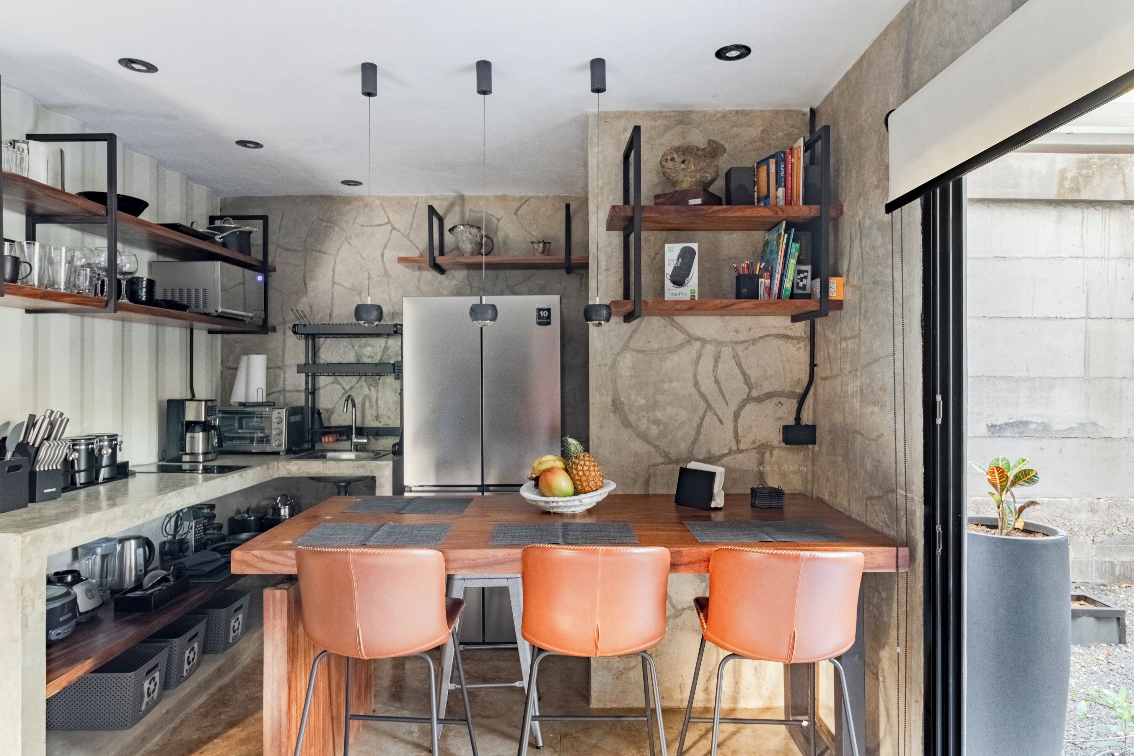 A modern kitchen with a central island, bar stools, and built-in shelves.