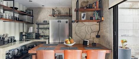 A modern kitchen with a central island, bar stools, and built-in shelves.