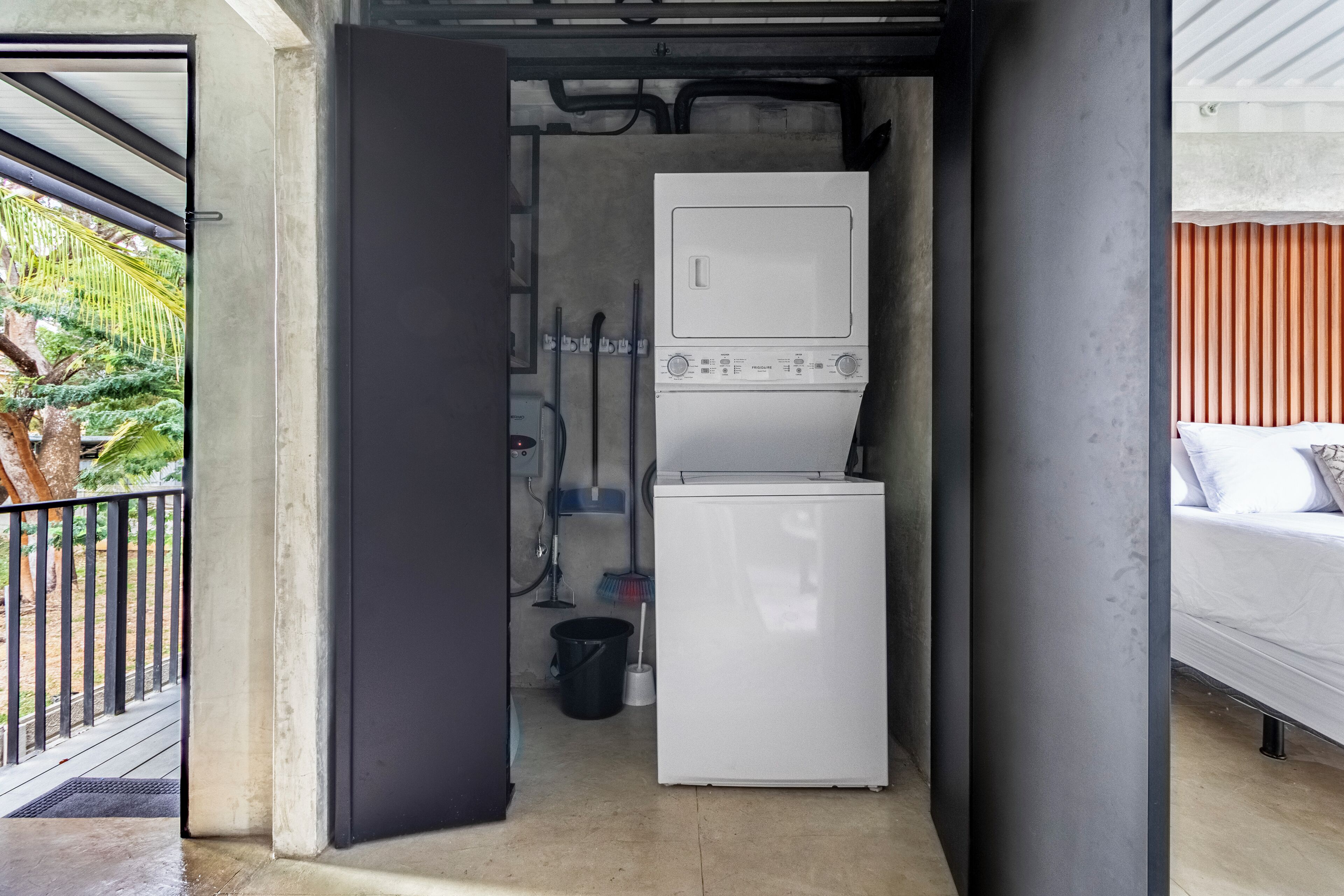 A compact laundry area with a washing machine and dryer, a mop, and a bucket.