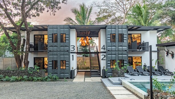 A modern two-story house with a unique design, featuring a central staircase, a pool area with lounge chairs, and a well-maintained garden. - Z102 studios (Potrero)