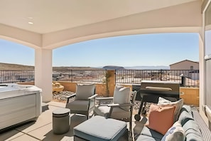 Relax on the balcony with a hot tub and seating area overlooking scenic hills.