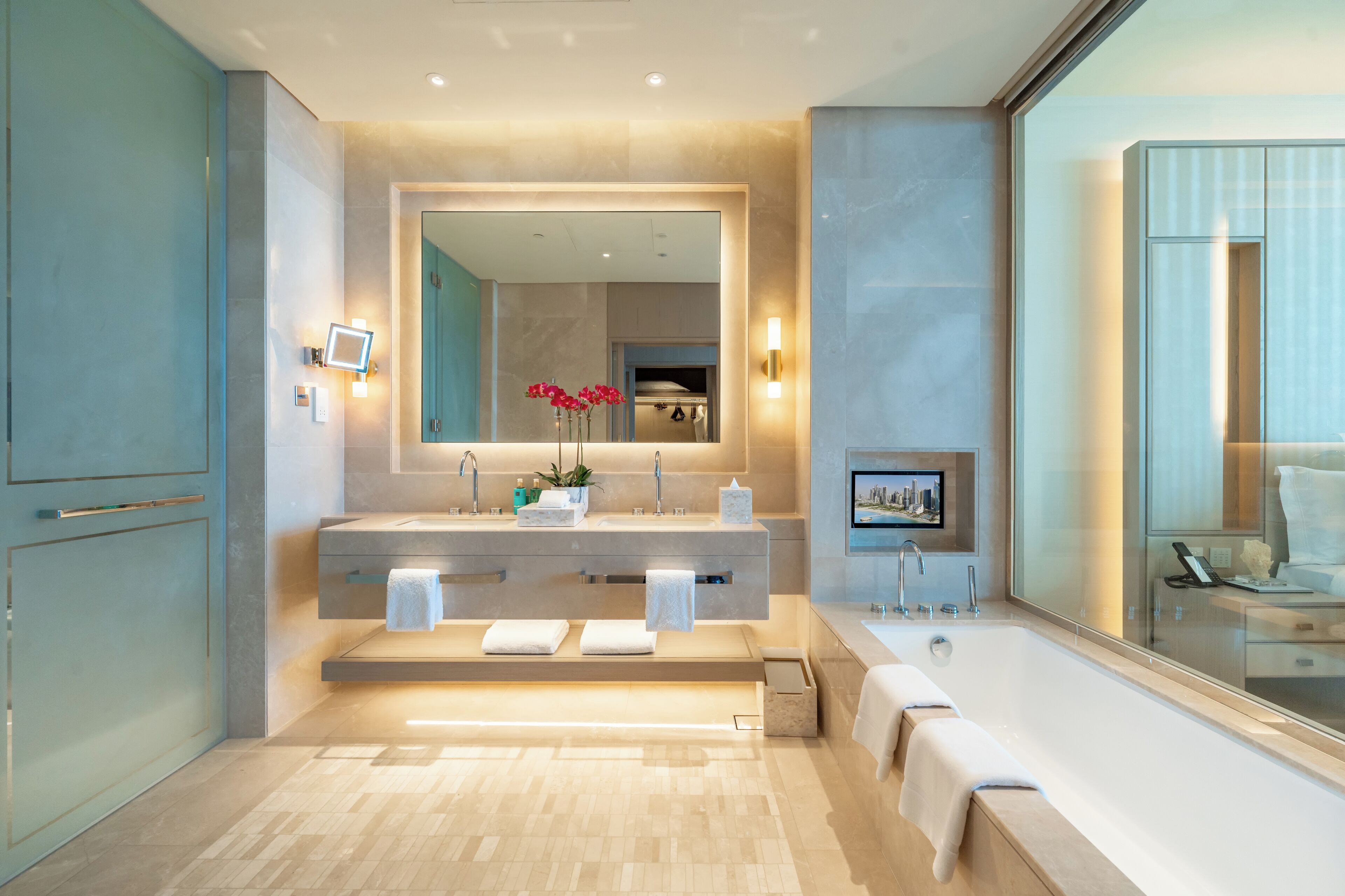 Un baño moderno con un espejo grande, dos lavamanos y una bañera.
