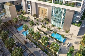 A modern building with a pool, palm trees, and a 'FIVE' sign. - Five Luxe JBR (Dubai)