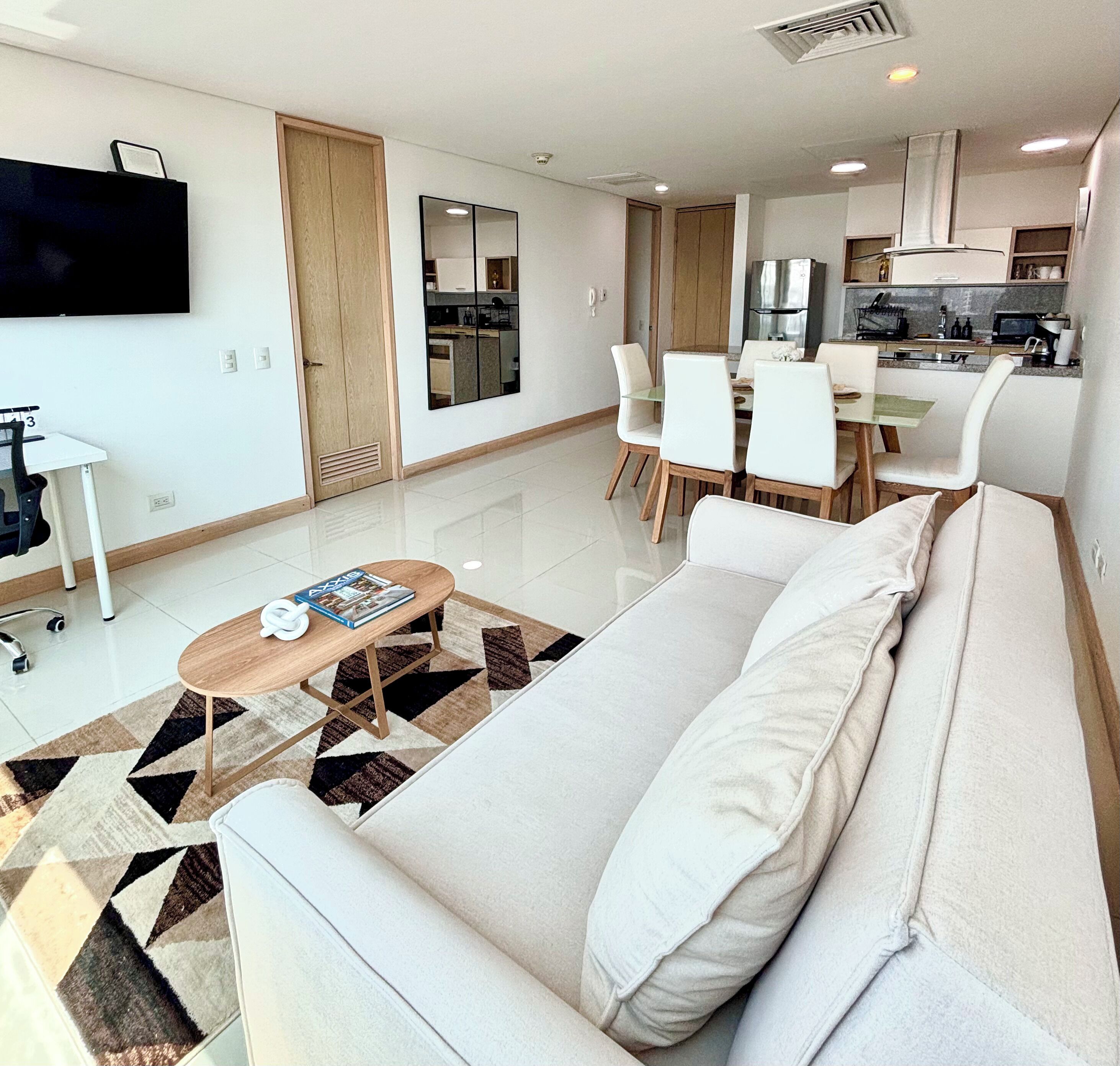 A modern living room with a sofa, coffee table, and dining area.