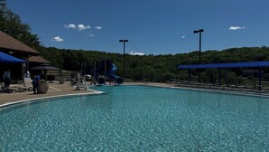 A clear blue pool with a slide, lounge chairs, and a covered seating area.