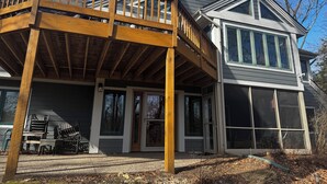 A two-story house with a wooden deck, large windows, and a covered porch.