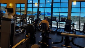 A gym with large windows, treadmills, and exercise equipment.