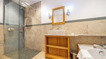 A bathroom with a glass-enclosed shower, a wooden vanity with a sink, and a bathtub.