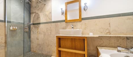 A bathroom with a glass-enclosed shower, a wooden vanity with a sink, and a bathtub.