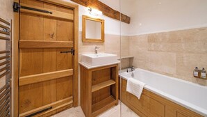 Una porta di legno con uno specchio sopra, un lavandino bianco e una vasca da bagno in un bagno.