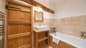 A wooden door with a mirror above it, a white sink, and a bathtub in a bathroom.