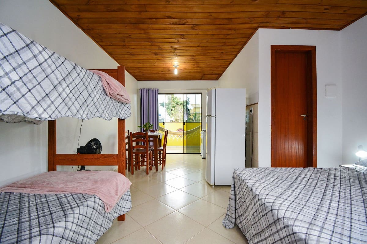 Ein Zimmer mit zwei Betten, Holzboden, einem Essbereich und einer Tür zum Außenbereich.