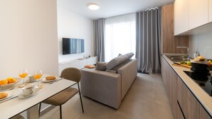 Ett modernt kök med matplats, en soffa och en tv med platt skärm.