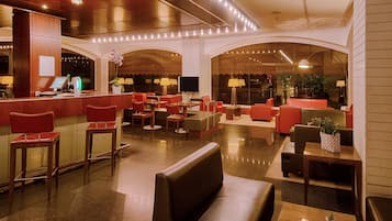 Eine geräumige Lobby mit Empfangstresen, Sitzbereichen und einem großen Fernsehbildschirm.