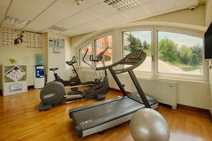 A gym with exercise equipment, a water dispenser, and a view of the outdoors.