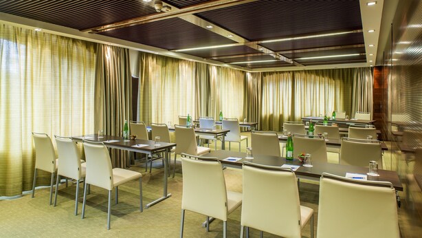 A conference room with tables and chairs, curtains, and ceiling lights. - Nh Hotel Milano 2 (Segrate)