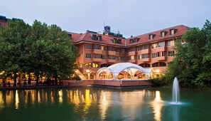 Un hotel con piscina, mobiliario exterior y una fuente.