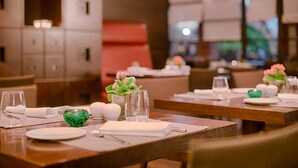A restaurant setting with tables set for dining, featuring clear glassware, plates, and small decorative vases. - Nh Hotel Milano 2 (Segrate)