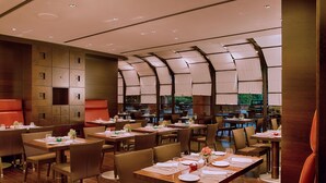 Un restaurante con varias mesas y sillas, un diseño interior moderno y vistas a zonas verdes.