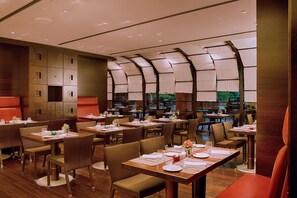 Un restaurante con varias mesas y sillas, un diseño interior moderno y vistas a zonas verdes.
