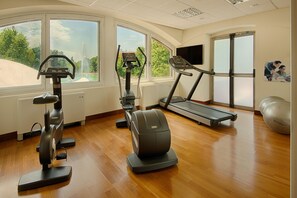 A gym with exercise equipment, large windows, and a treadmill. - Nh Hotel Milano 2 (Segrate)