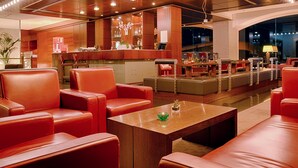 A modern lobby with leather seating, a reception desk, and a bar area. - Nh Hotel Milano 2 (Segrate)