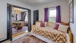 A bedroom with a large bed, a dining area with a round table, and a view of the outdoors. - New 5BD Near UNL & DT - Poker Table & Games (Lincoln)