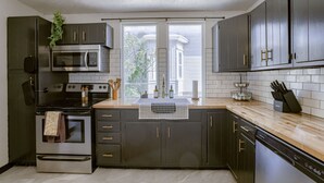A modern kitchen with dark cabinets, stainless steel appliances, and a wooden countertop. - New 5BD Near UNL & DT - Poker Table & Games (Lincoln)
