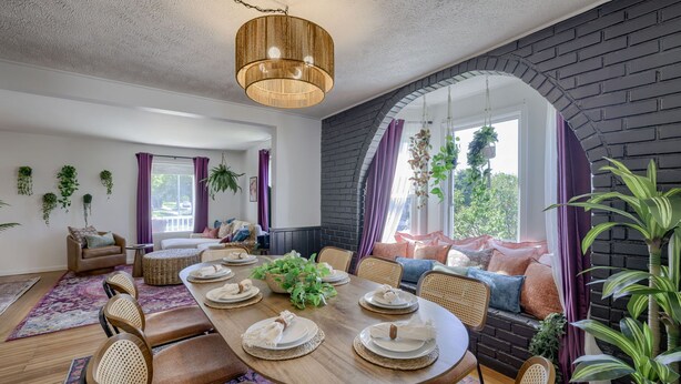 A dining area with a round wooden table set for six, surrounded by wicker chairs. - New 5BD Near UNL & DT - Poker Table & Games (Lincoln)