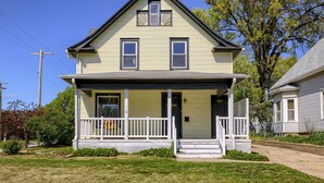 A two-story house with a front porch, a small entryway, and a visible front door. - New 5BD Near UNL & DT - Poker Table & Games (Lincoln)