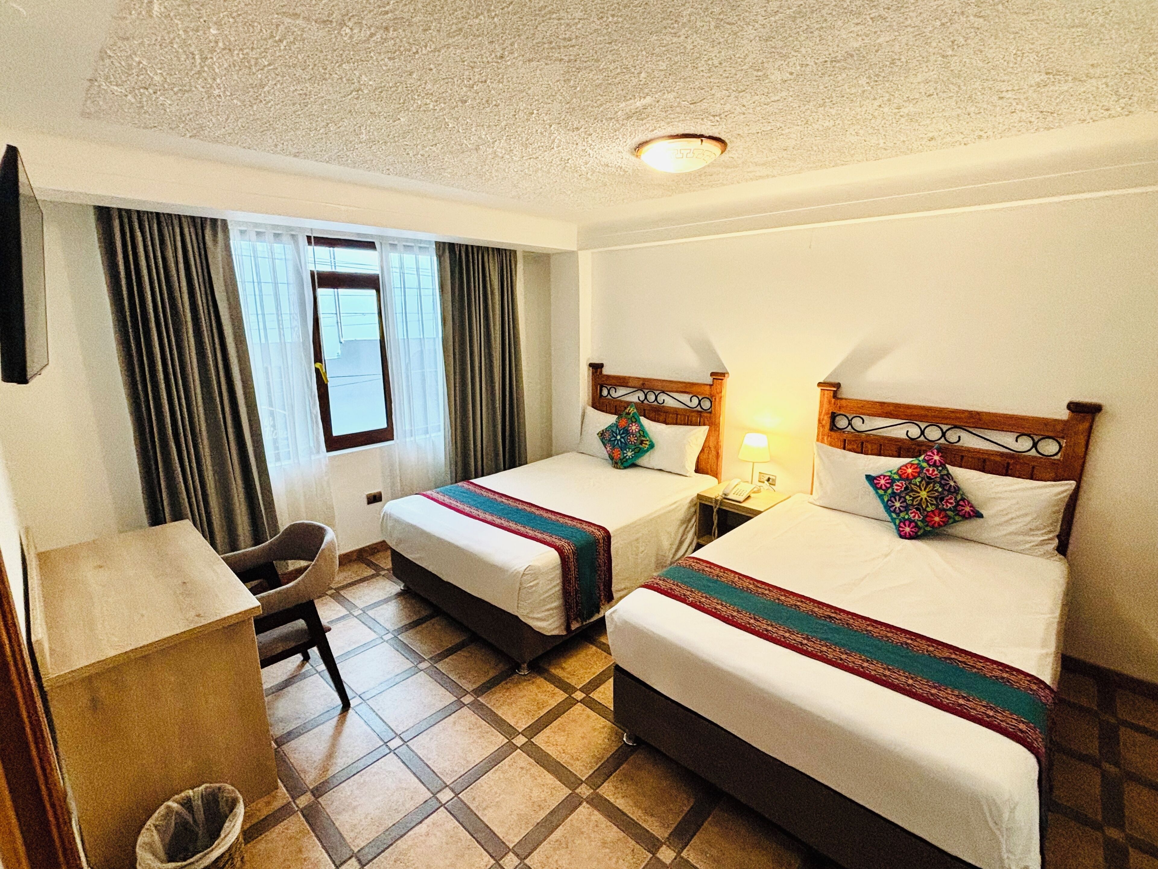 A hotel room with two beds, a desk, and a chair.