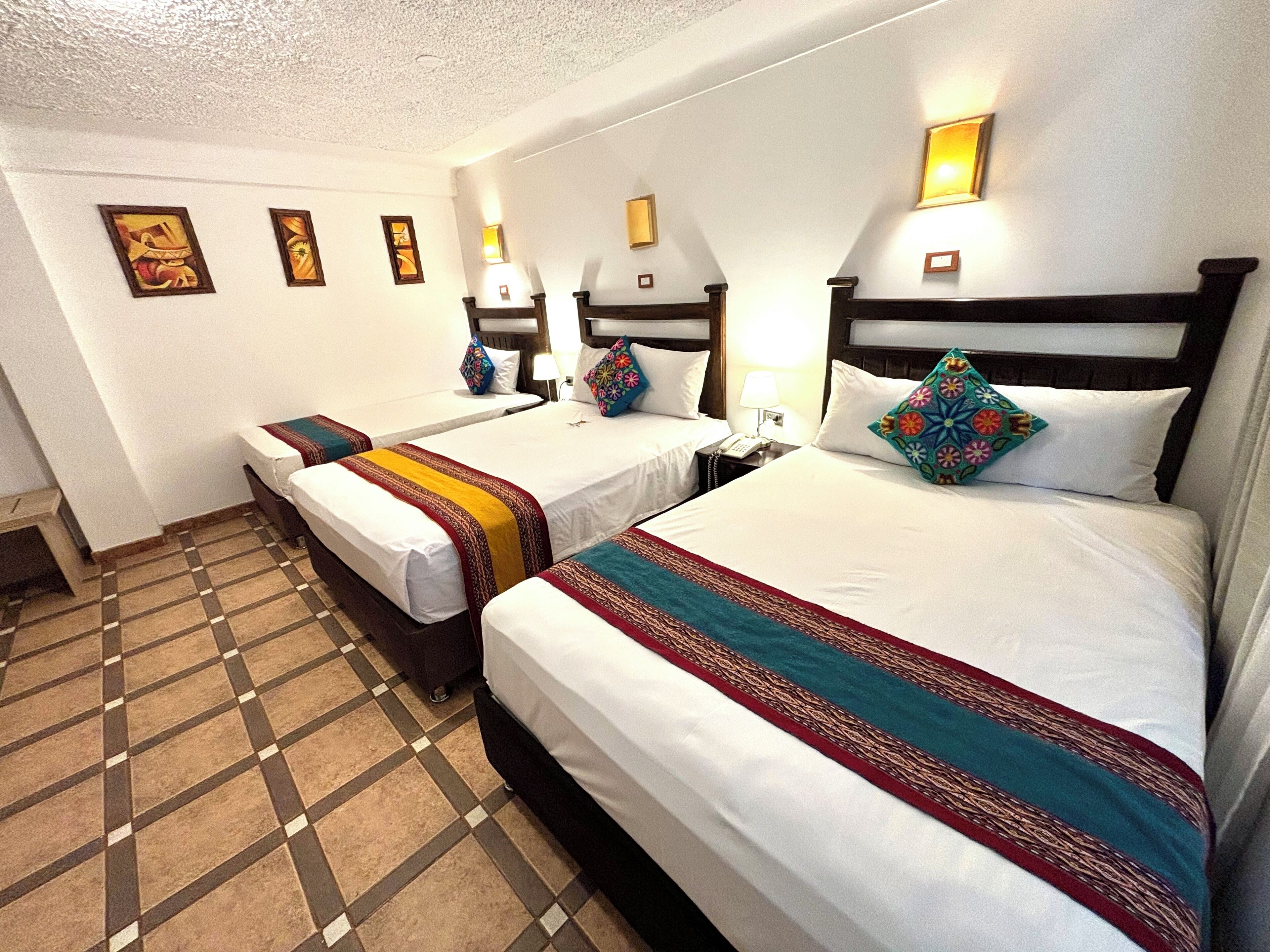 Habitación de hotel con dos camas, una recepción y piso de baldosas.
