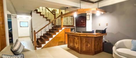 Amplia sala de estar con una escalera de madera, una zona de bar y un conjunto de asientos.