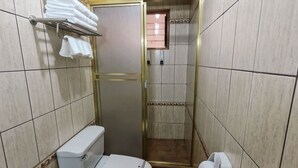 A small bathroom with a toilet, a trash can, a towel rack with towels, and a paper towel dispenser. - Hotel Rojas Machupicchu (Aguas Calientes)