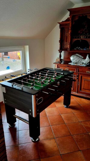 Enjoy a game of Foosball in this room with a view of the outdoor area, featuring a window and a decorative cabinet with a fish sculpture.