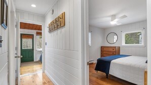 A bedroom with a bed, a dresser, a mirror, and a window.