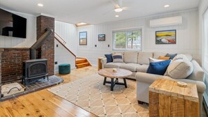 A cozy living room with a fireplace, a sofa, a coffee table, and a staircase.