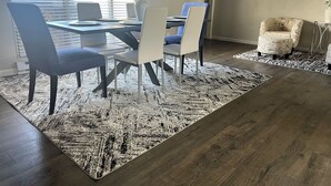 Ein Essbereich mit Tisch und Stühlen, einem gemusterten Teppich und einem Stuhl mit markantem Design.