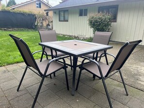 Een terras met een tafel en vier stoelen.