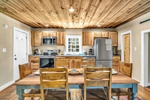 Une cuisine avec des meubles en bois, un îlot central et une table à manger avec des chaises.