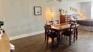 A dining area with a wooden table and chairs, a ceiling fan, and a bed in the background. - Downtown studio apartment with ROOFTOP DECK (Bloomington)