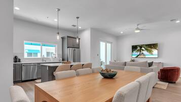 A modern kitchen with a dining area, a large window, and a ceiling fan.