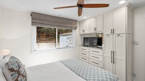 A bedroom with a bed, a television, a wardrobe, and a window with a view of a truck outside.