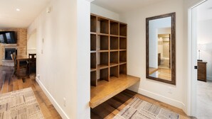 A hallway with a wooden bench, a mirror, and a TV mounted on the wall. - Crestwood 1201 Premier 3 Bedroom (Snowmass Village)