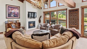 A spacious living room with a large sofa, a fireplace, and a chandelier.
