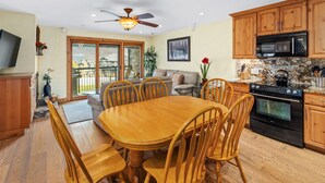 Une cuisine spacieuse avec des meubles de rangement en bois, un coin repas avec une table et des chaises en bois, un grand four et un ventilateur de plafond.