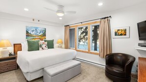 A bedroom with a bed, a chair, a TV, and artwork on the walls.