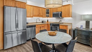 A modern kitchen with wooden cabinets, stainless steel appliances, a granite countertop, and a round dining table with chairs.